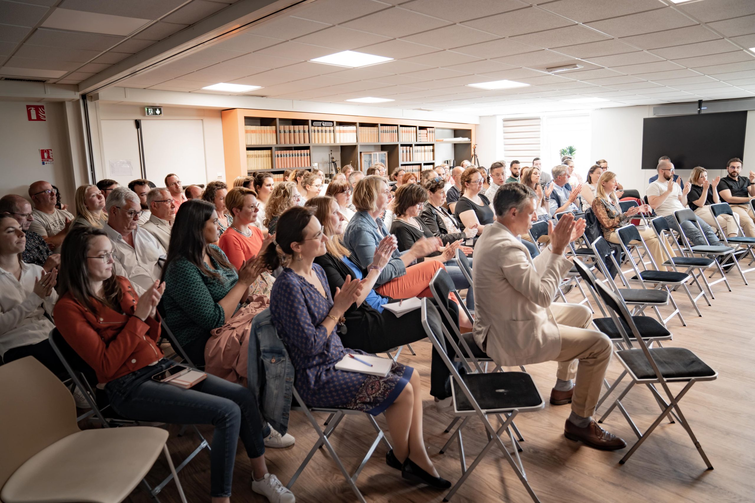 une salle avec de nombreuses personnes assises qui applaudissent